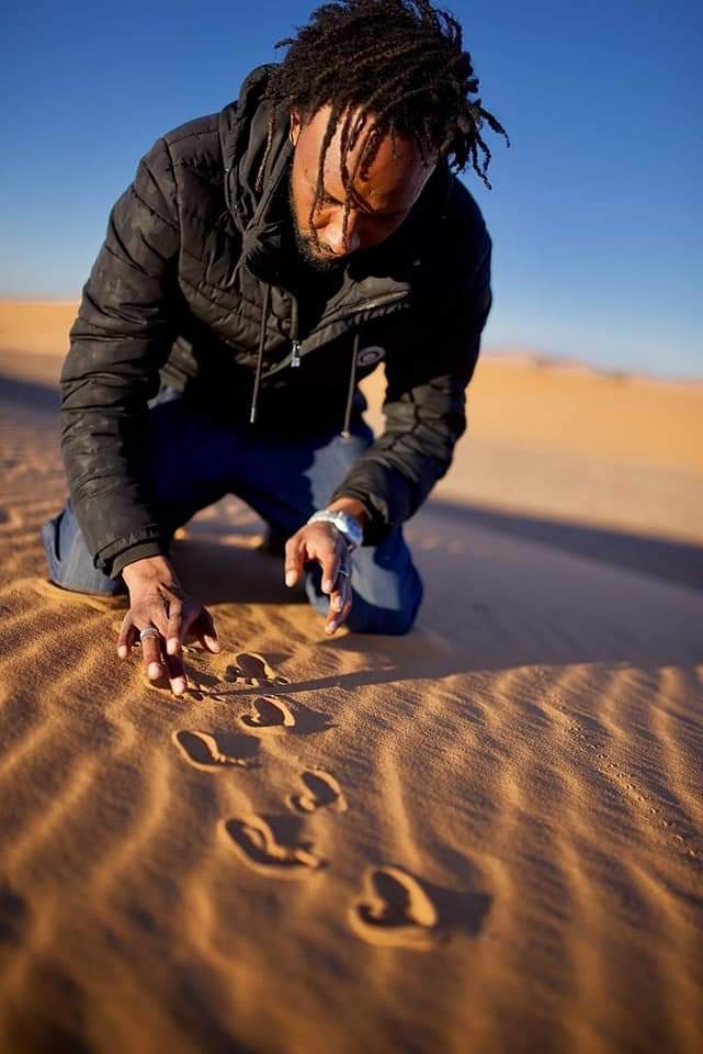 Rachid forme des traces d'animaux dans le sable du désert